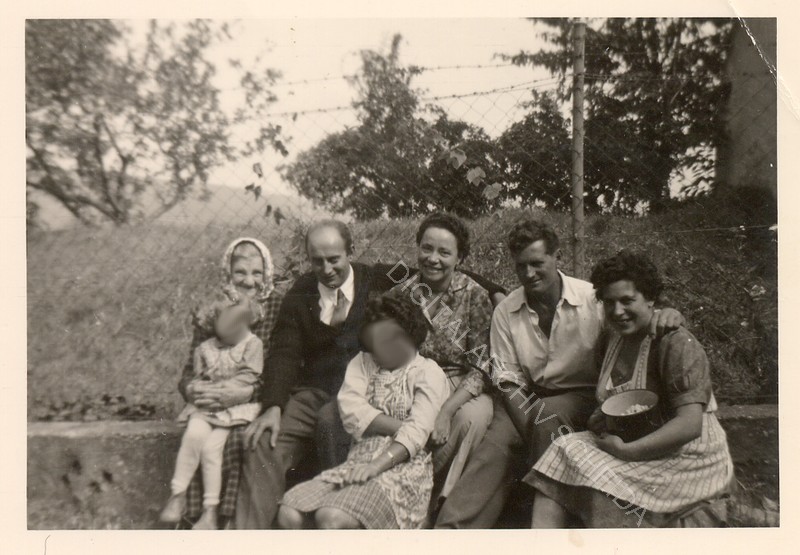 Am Aufgang vom Haus in den Garten: Sitzen an der Begrenzungsmauer vom Zaun zu den Fraissl Presshaus und Weingarten. Von Links: Frau Schweiger Mutter, verm. der 2. Sohn von Frau Schweiger, Frau Fraziska Kittel, Anton Schweiger, Eveline Schweiger und zwei Kinder.